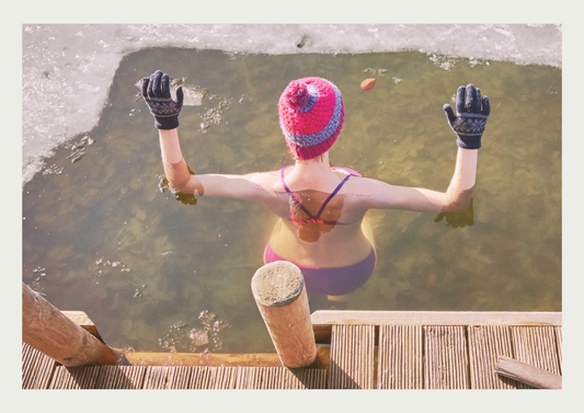 A woman in a beanie hat dipping in ice water.