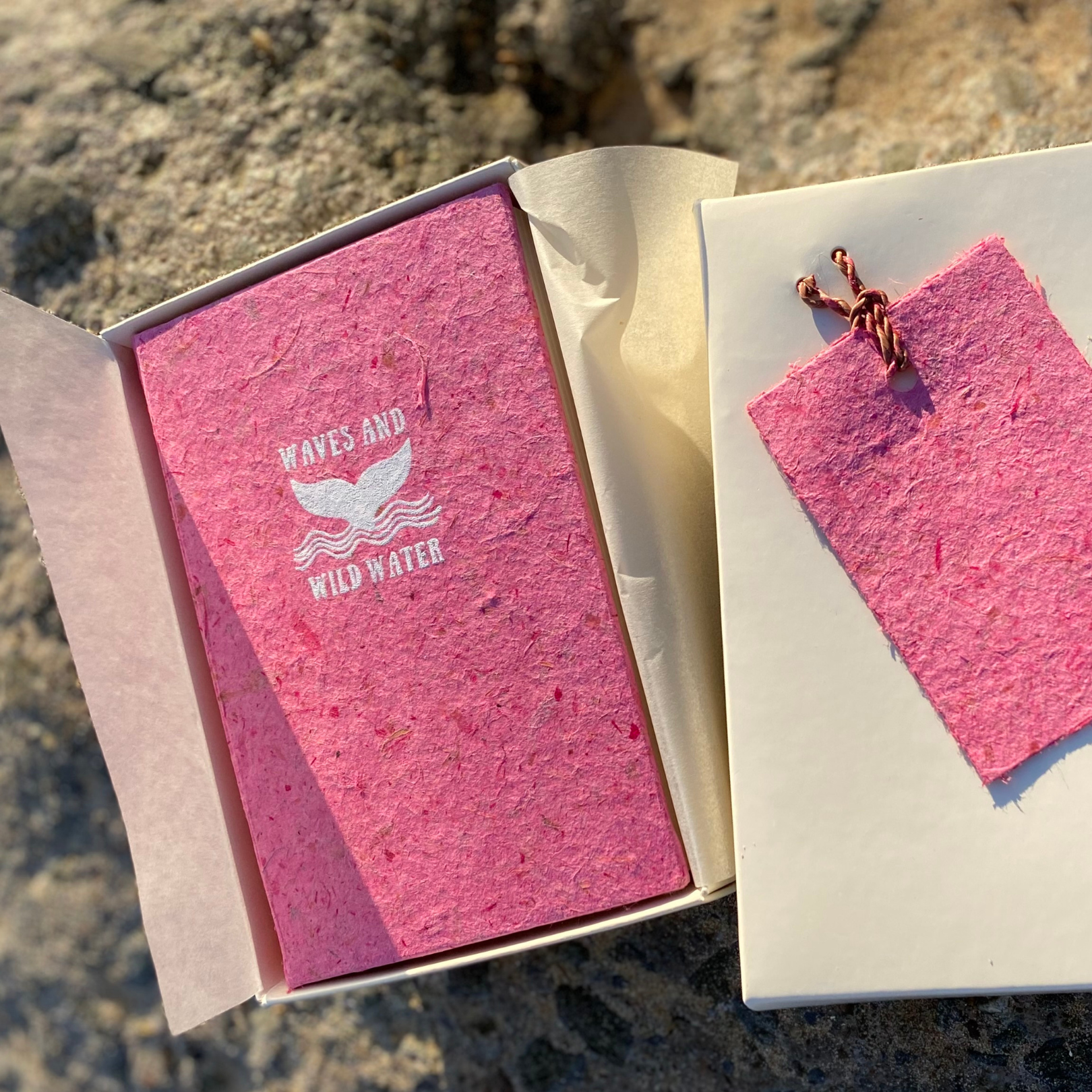 An off-white box with a pink notebook in it.
