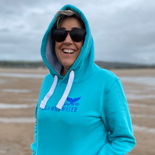 A woman wearing a lagoon blue hoodie with the hood up.