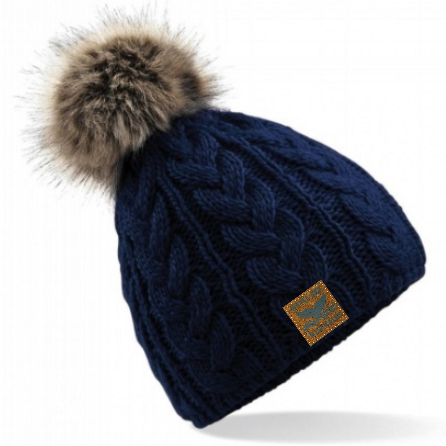 Waves and Wild Water gorgeous deep navy cable knitted beanie hat with fun furry pom pom. Perfect for keeping your head cosy after a sea dip, cold water plunge, or during a hike up the mountains!