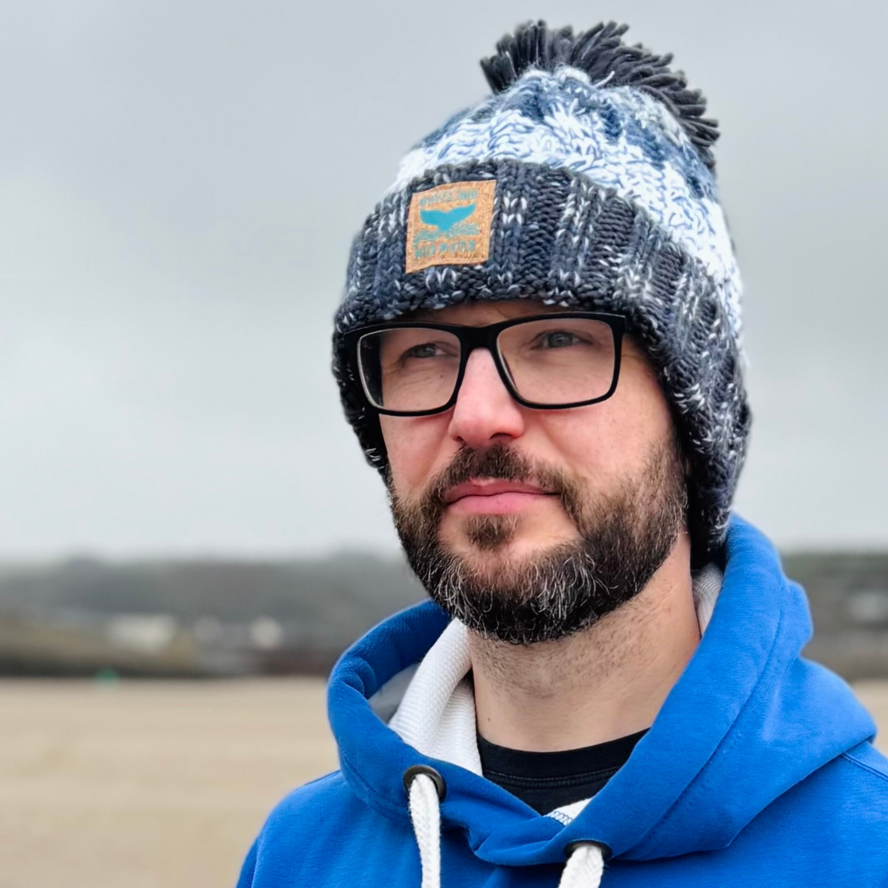 Waves and Wild Water owner Glenn, looks out across the sea at the rapidly approaching rain clouds and thanks the stars that he wore his extra thick and cosy knitted beanie hat in Frosty Morning grey.