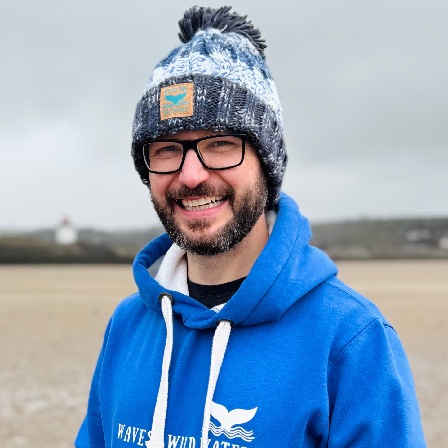 Wild swimmer Glenn, looks super warm and cosy in his Frosty Morning Grey knitted beanie hat with plump pom pom.