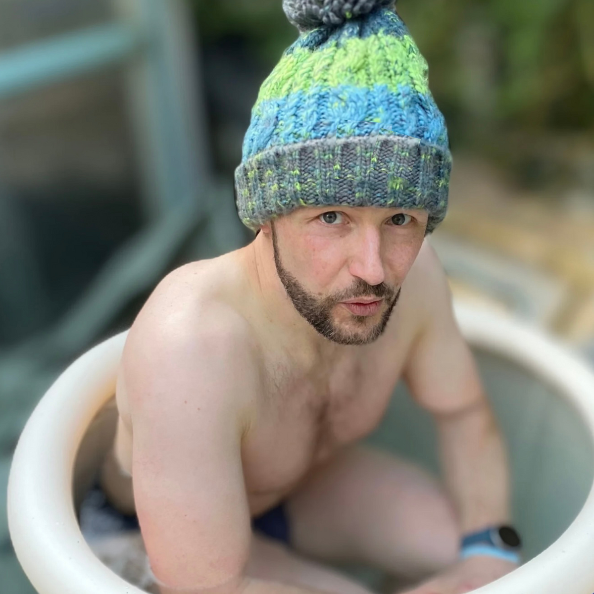 Waves and Wild Water owner, Glenn, works on his cold tolerance in an ice tub. Following advice from cold water therapist Claire, he stops the heat leaving through his head by wearing his Lagoon knitted beanie hat.