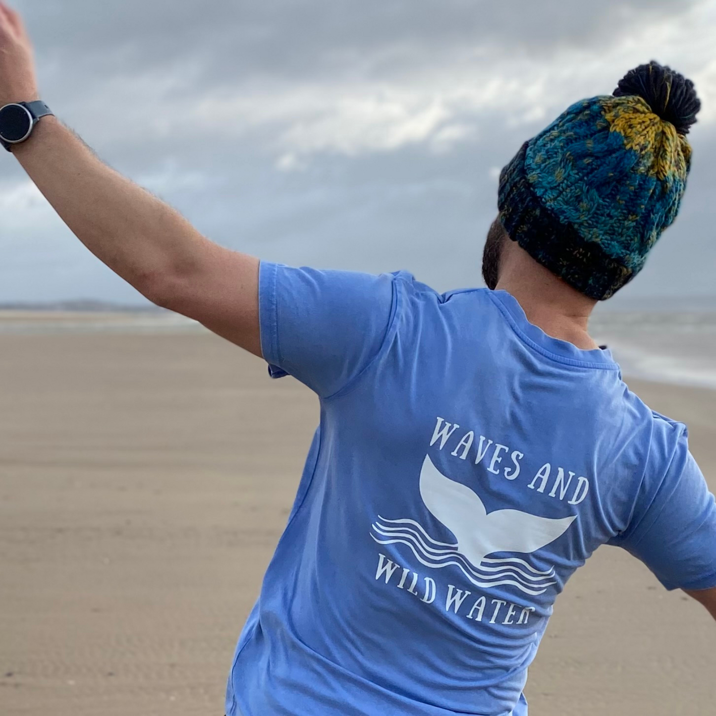 Wild swimmer Glenn, has a bit of a play on the beach whilst wearing his Ocean Depths knitted beanie hat and his Swimmer Blue Waves and Wild Water t-shirt.