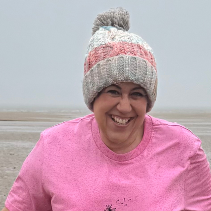 Waves and Wild Water owner Claire, tries to keep smiling on a very cold and wet day on the beach, while wearing her Seashell Pink knitted beanie hat and pink t-shirt.