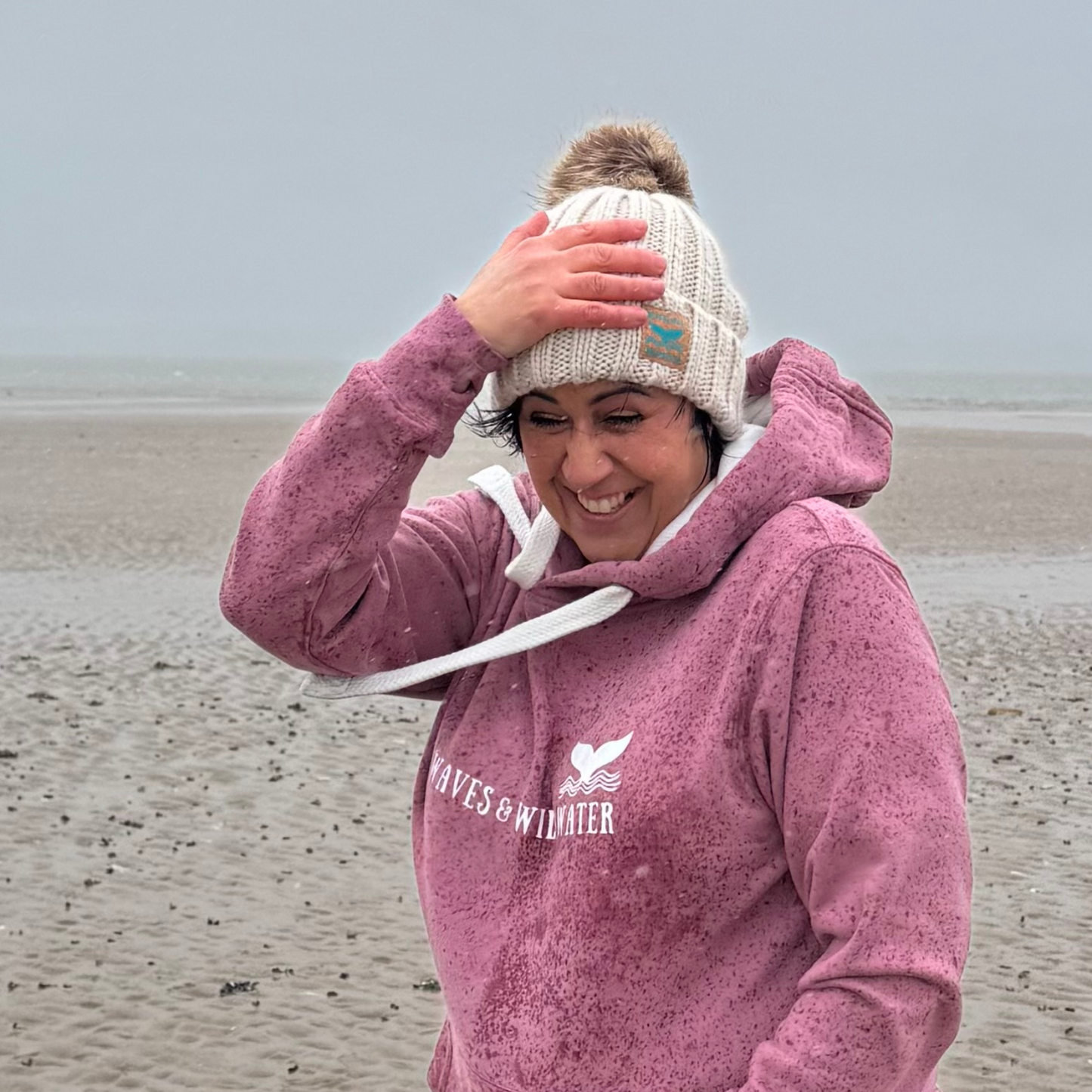 Wild swimmer and sea dipper Claire, is glad she's not in the sea on such a cold and rainy day in South Wales. She's super glad she's cosy in her Winter Swim knitted beanie hat and coordinating Sunset Blush hoodie instead.