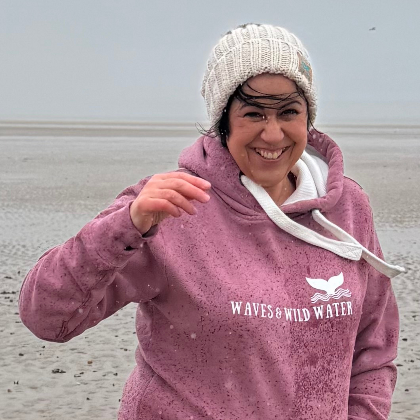 It's wet and windy on the beach in Burry Port, but Waves and Wild Water owner Claire, is wearing her cream coloured Winter Swim knitted beanie hat and coordinating Sunset Blush hoodie, so she's lovely and cosy.