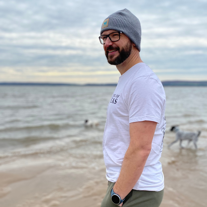 Glenn wears his Waves and Wild Water fisherman beanie hat on the beach as the dogs play in the sea. The Frosty Morning grey of his hat suits the day but not his mood - like every wild swimmer, he looks absolutely thrilled to be near the water!