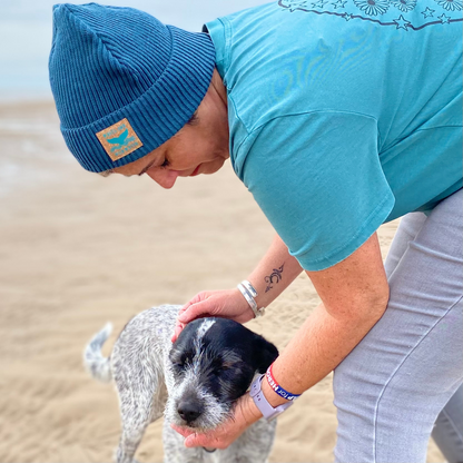 Waves and Wild Water owner Claire, says a quick hello to her dog during a walk on the beach. It's a little chilly so Claire is keeping her head warm and cosy in her Stormy Sea knitted fisherman beanie hat.