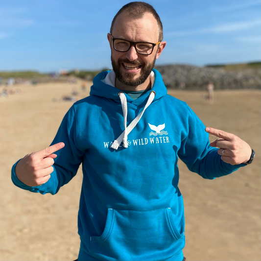 Waves and Wild Water owner Glenn, is enjoying a sunny day on the beach in Wales. Despite the sun, it's a bit chilly, so he's staying warm in his stunning Tropical Waters hoodie. The white logo print across the chest compliments the white inner hood and chunky draw cords.