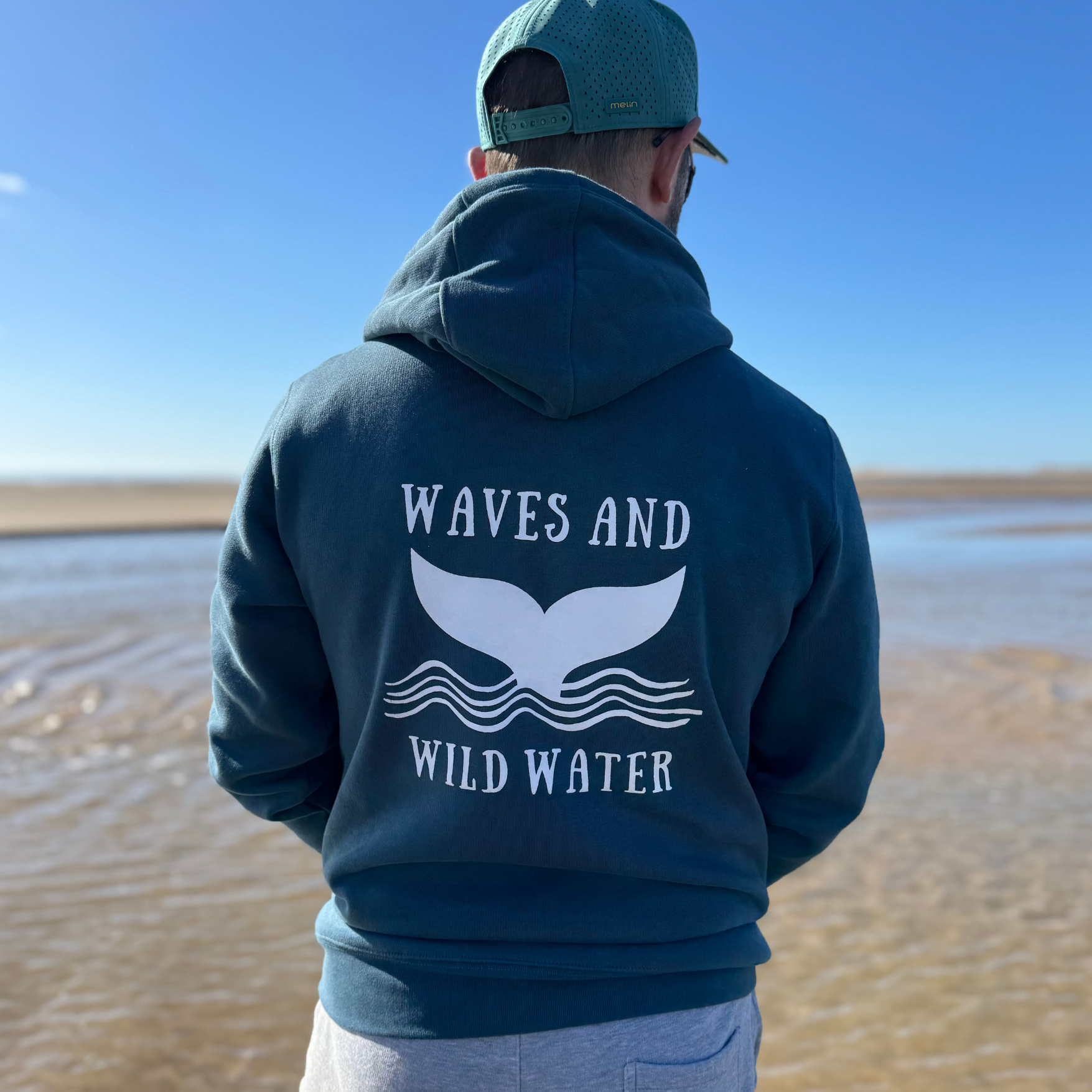 Waves and Wild Water owner and wild swimmer Glenn, wears his gorgeous Stormy Sea hoodie to stay warm and cosy during his walk on the beach in Wales.