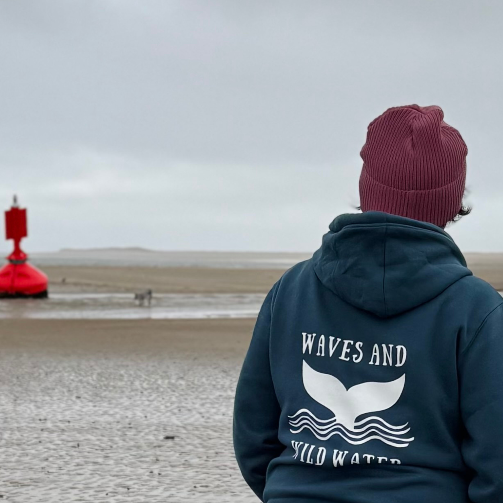 Wild swimmer Claire's Stormy Sea hoodie is quite apt for her walk today, as she pauses to watch the rain clouds coming across the sea from the Gower.