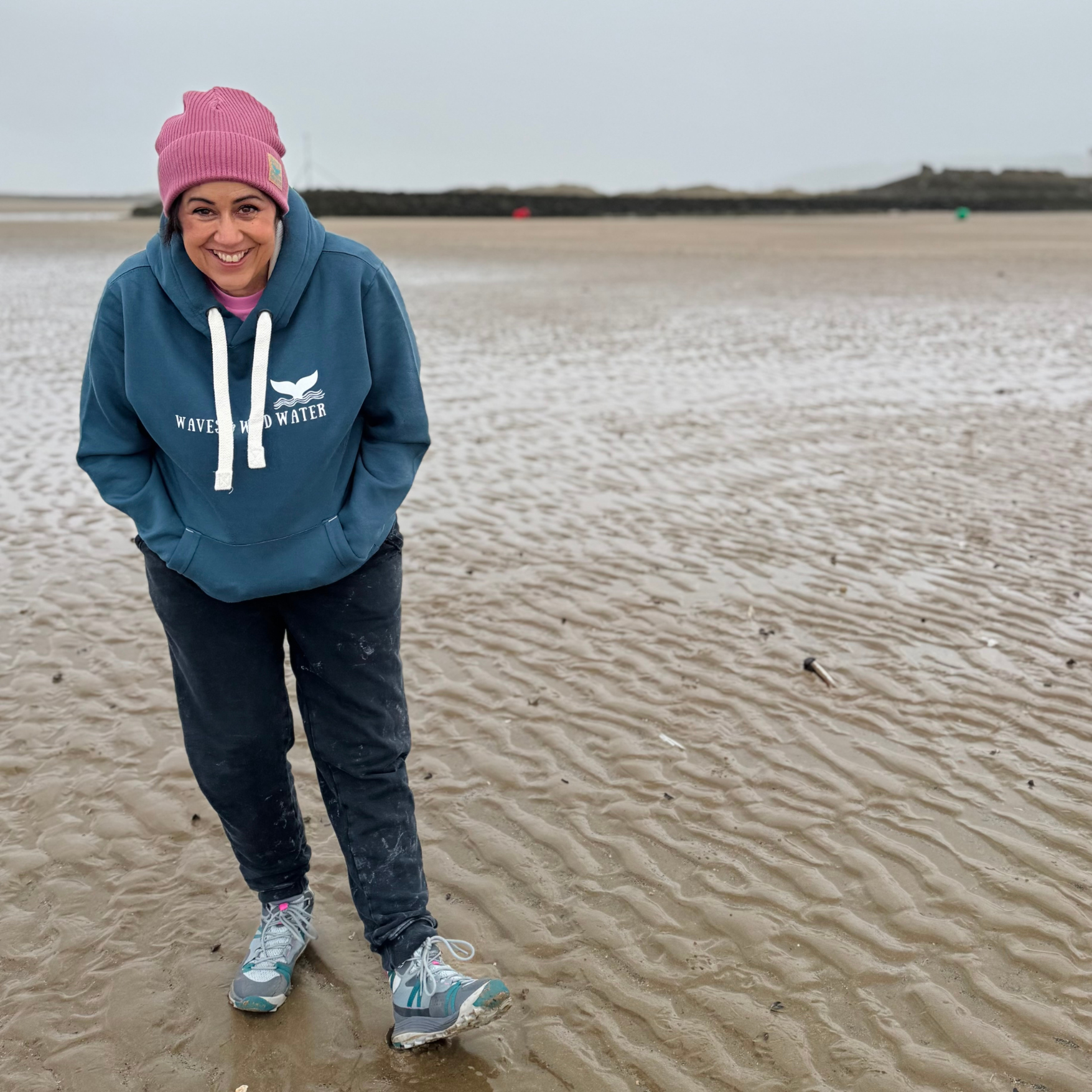 Waves and Wild Water owner Claire, looks happy to be snug and warm in her Stormy Sea hoodie as she enjoys a blustery walk on the beach.