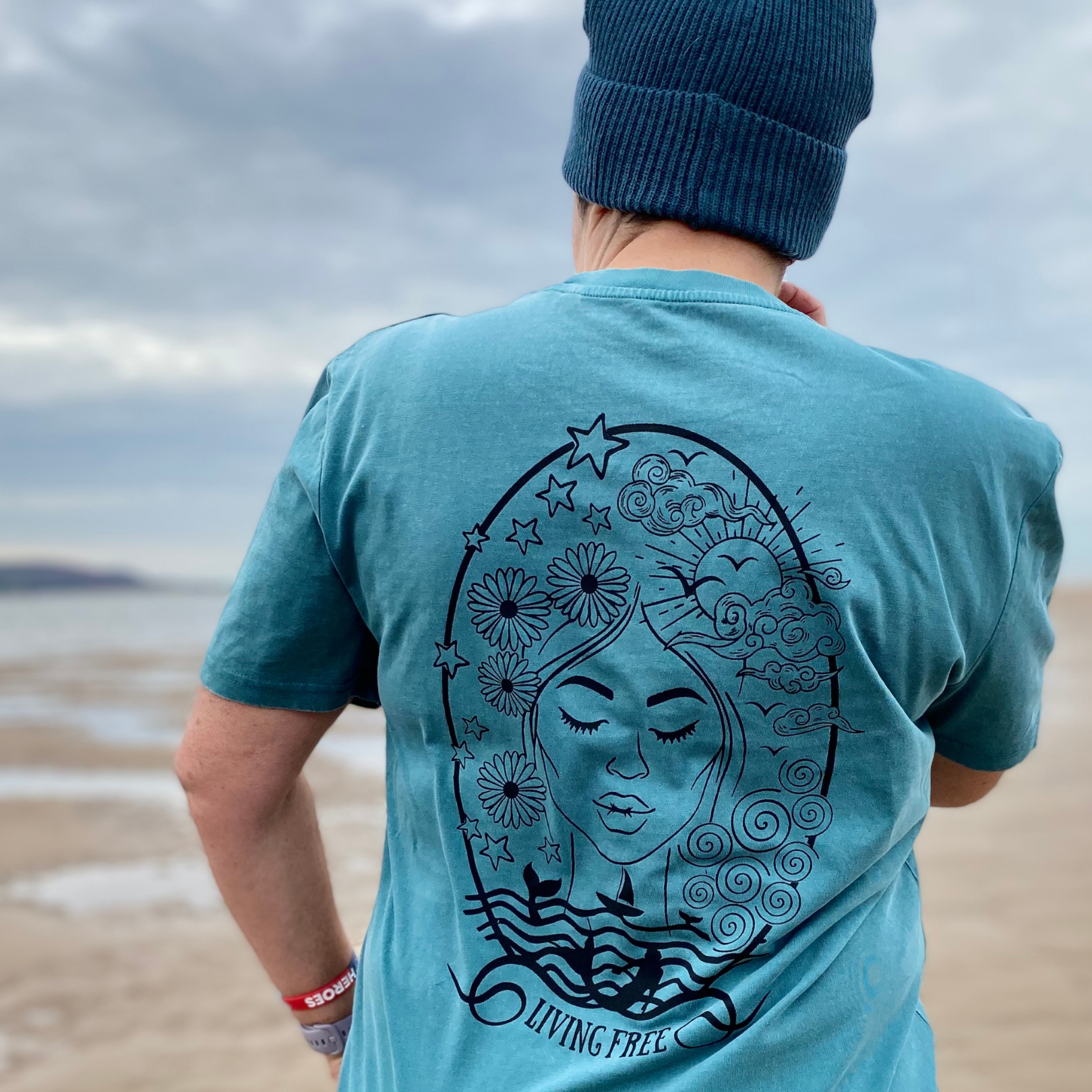 A Waves and Wild Water favourite, this seafoam green organic t-shirt depicts a serene woman's face amid a magical collection of waves, flowers, and frolicking mermaids.