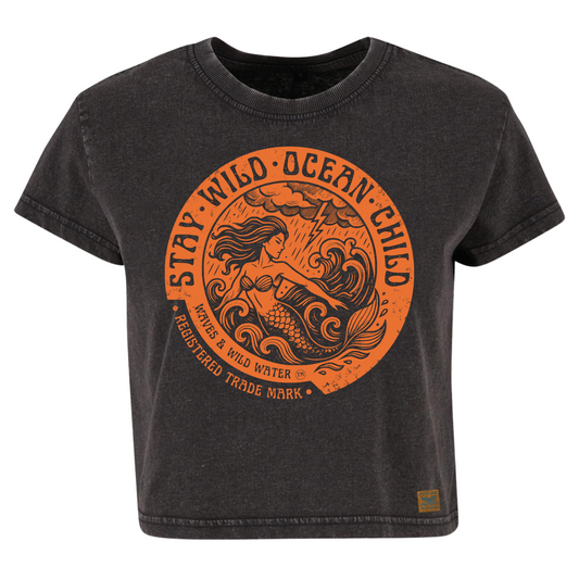 Vintage black cropped sustainable cotton t-shirt with metallic copper ink design of a mermaid in stormy seas, framed by Stay Wild Ocean Child text. Designed and printed by Waves & Wild Water, and loved by rock chick mermaids!
