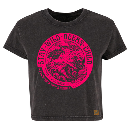 Vintage black cropped sustainable cotton t-shirt with bright magenta ink design of a mermaid in stormy seas, framed by Stay Wild Ocean Child text.