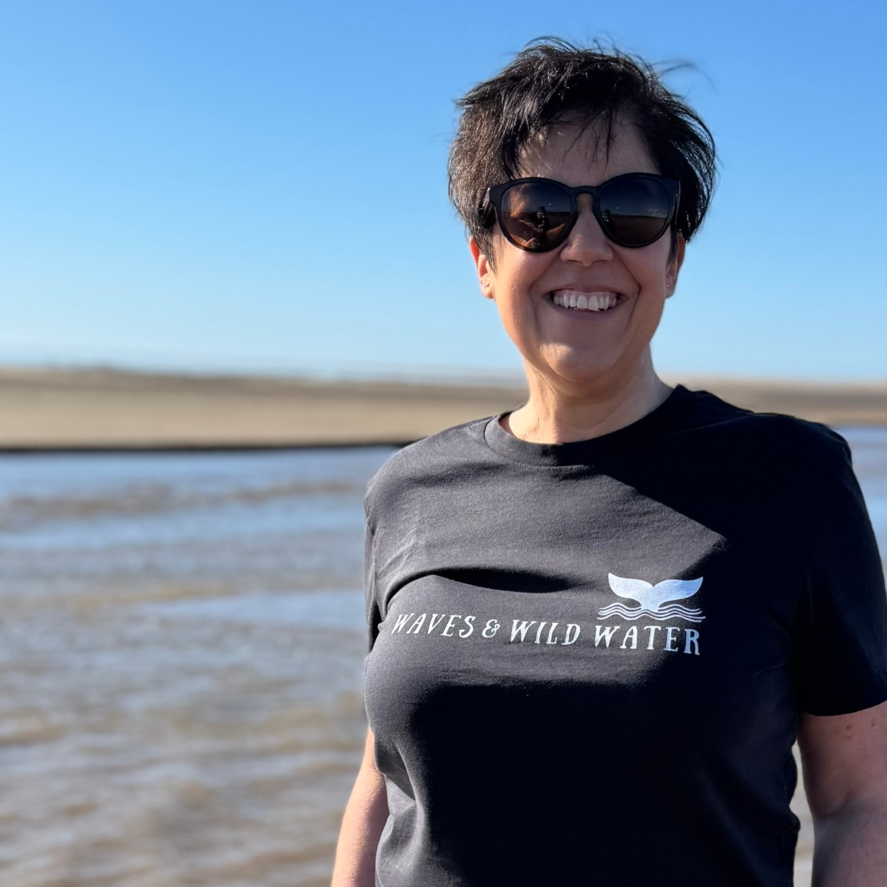 Wild swimmer Claire, enjoys a break in the weather and the appearance of the sun! She's wearing her Waves and Wild Water t-shirt in Night Sky black.