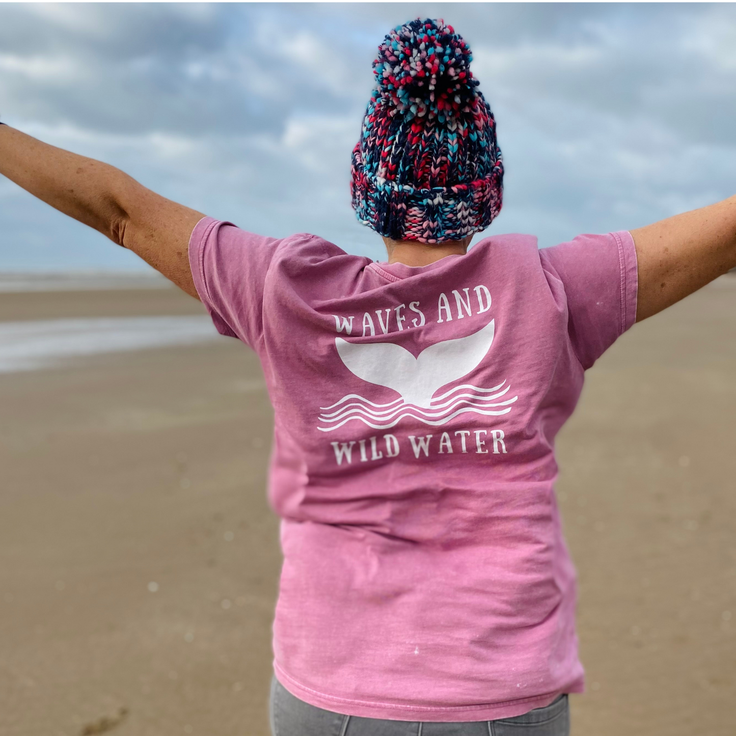 Waves and Wild Water owner, and keen wild swimmer, Claire wears her pink Seashell Pink t-shirt on the beach during a break in the Welsh weather.