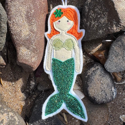 Wild Water Mermaid decoration with shimmering green tail resting among seaside stones, a unique handmade coastal gift - only from Waves & Wild Water.
