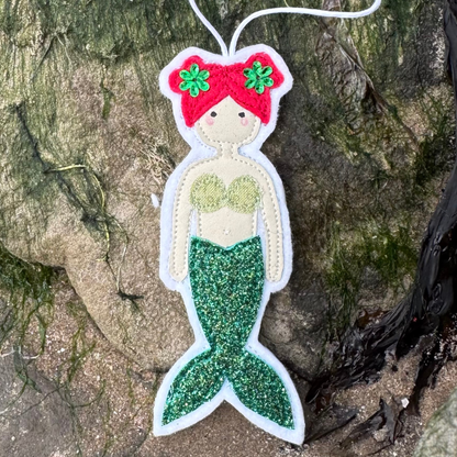 Handmade green glitter tail mermaid hanger with coordinating bikini top displayed on coastal rocks. Only from Waves & Wild Water - a perfect gift for the wild wannabe mermaid in your life.