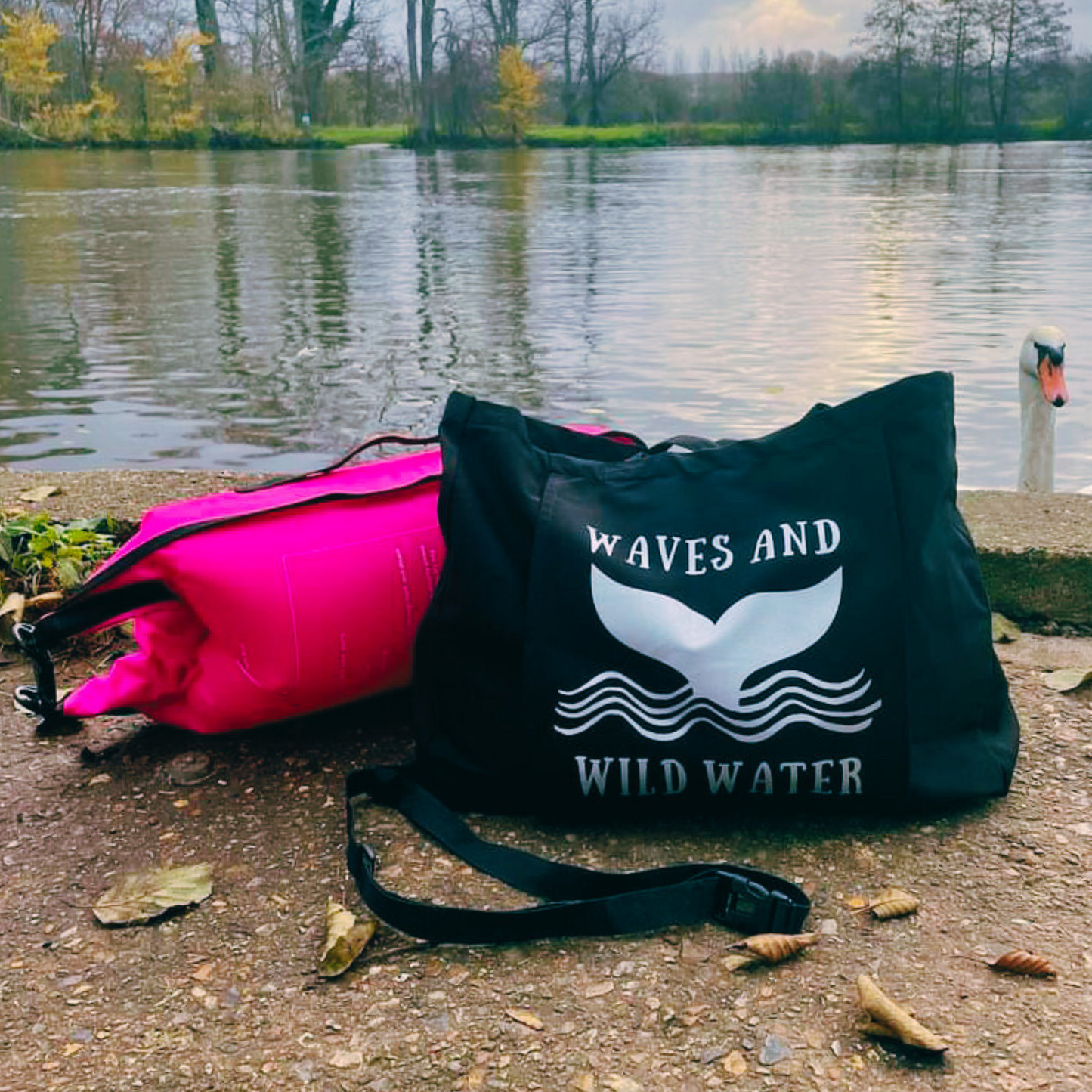 Black tote bag with wave design in front of a river backdrop.