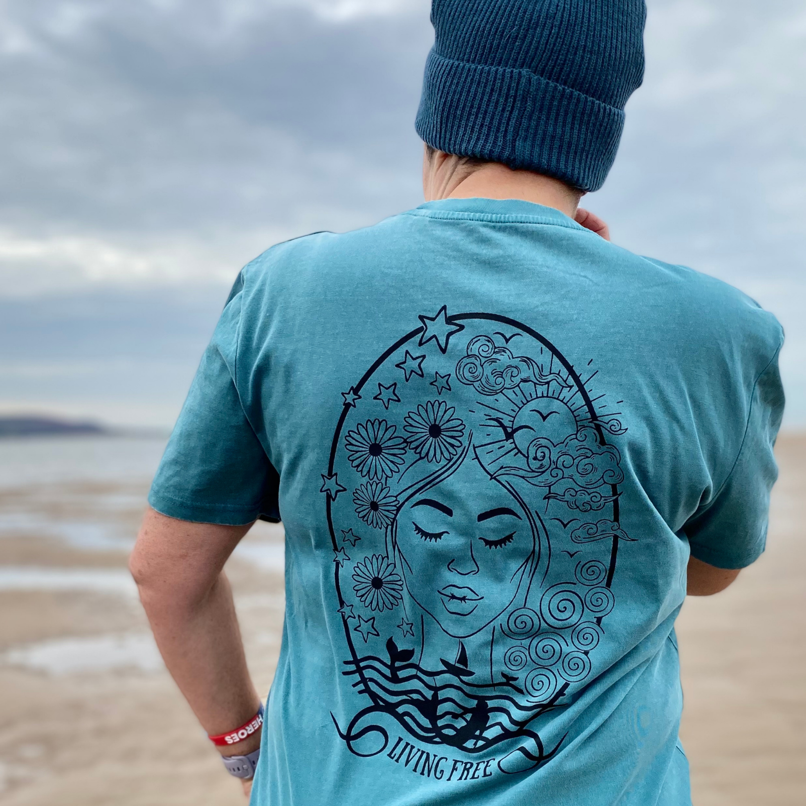 A woman's back, showing a seafoam green t-shirt with a print of a woman's face on it.