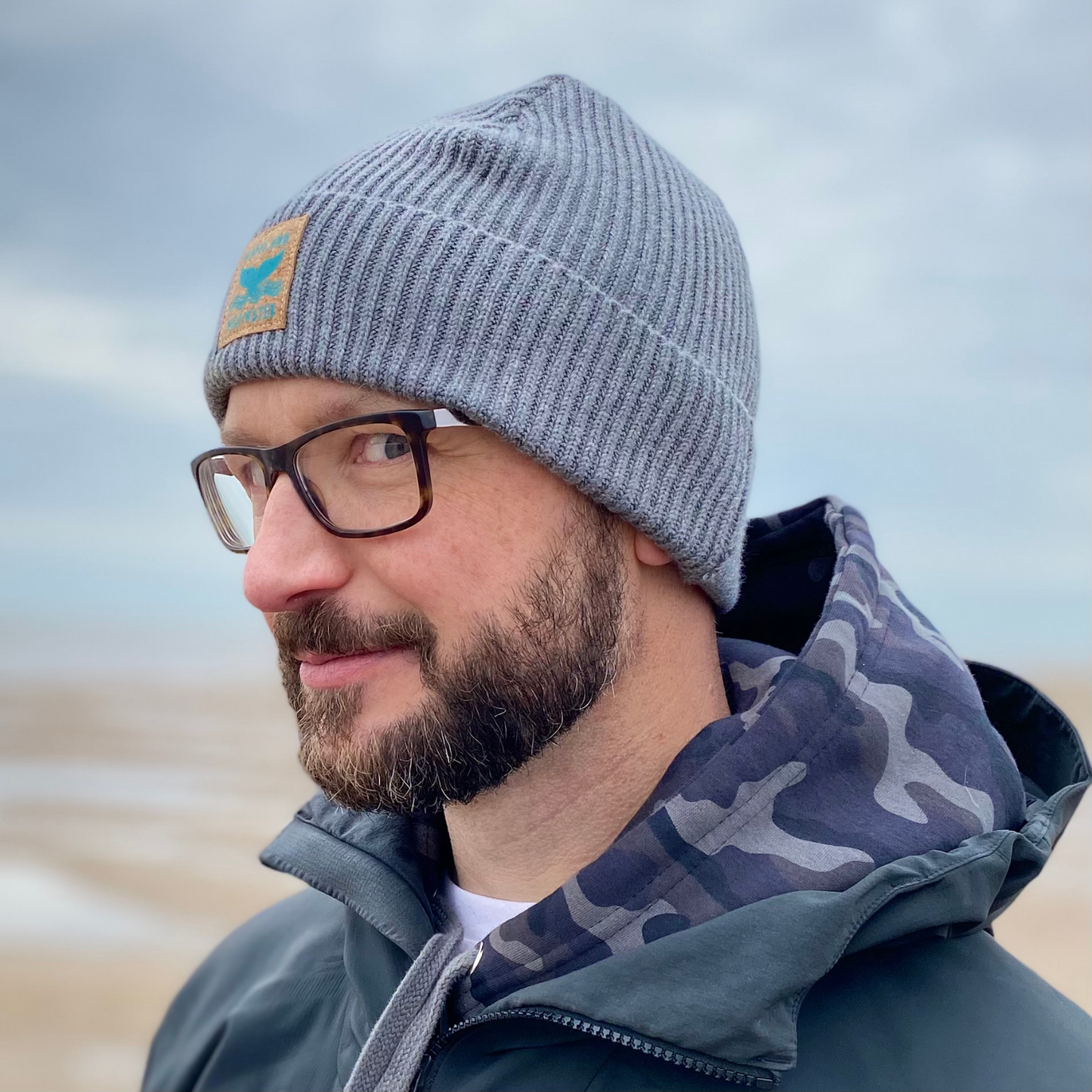 A man with a beard wearing glasses and a grey fisherman beanie hat.