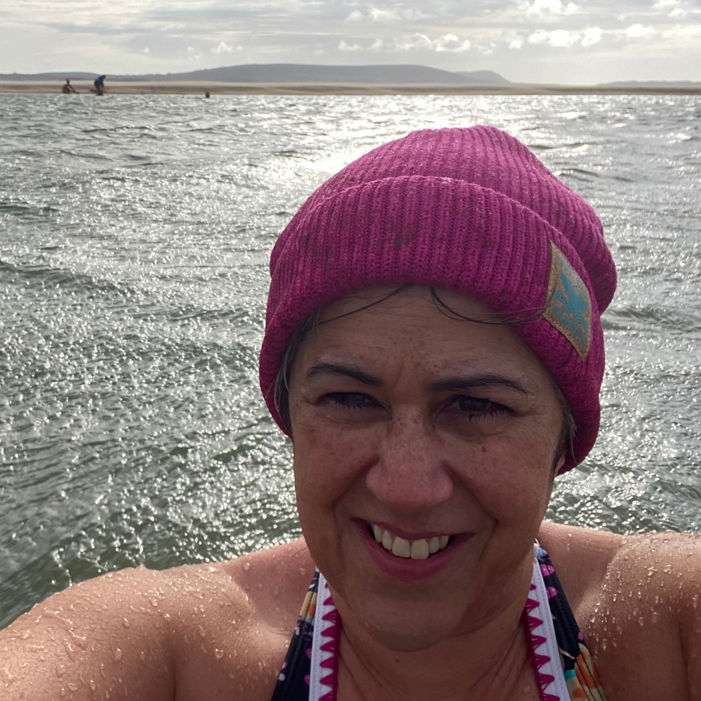 A woman in the sea wearing a pink fisherman beanie hat.